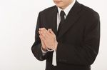 数珠を持って拝んでいる喪服姿の男性
