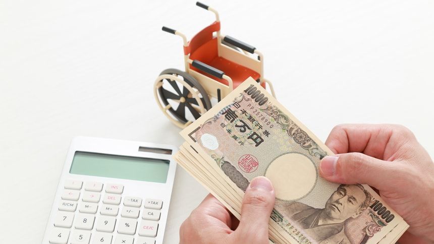 車椅子の模型と電卓と札束