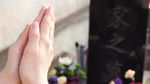 供花が供えられた墓前で合わせている両手