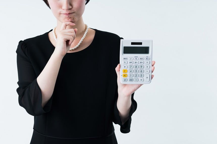 電卓を持って考える喪服の女性
