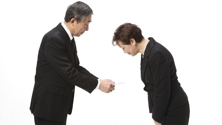 香典を渡す男性と、受け取る女性
